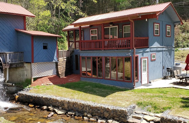 Rustic two-story cabin on creek with covered bridge and water wheel.