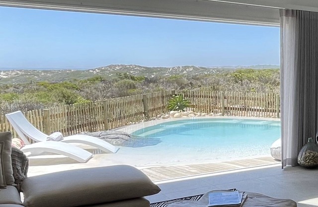Tranquil haven: home in nature's embrace, where ocean and dunes unite.